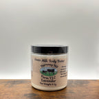 Jar of lavender goats milk body butter on a wooden surface with a white background