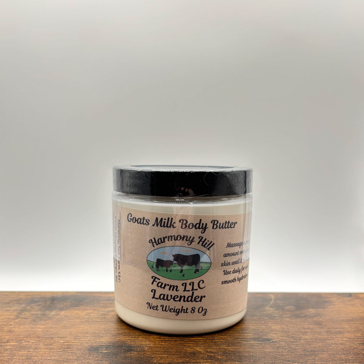 Jar of lavender goats milk body butter on a wooden surface with a white background