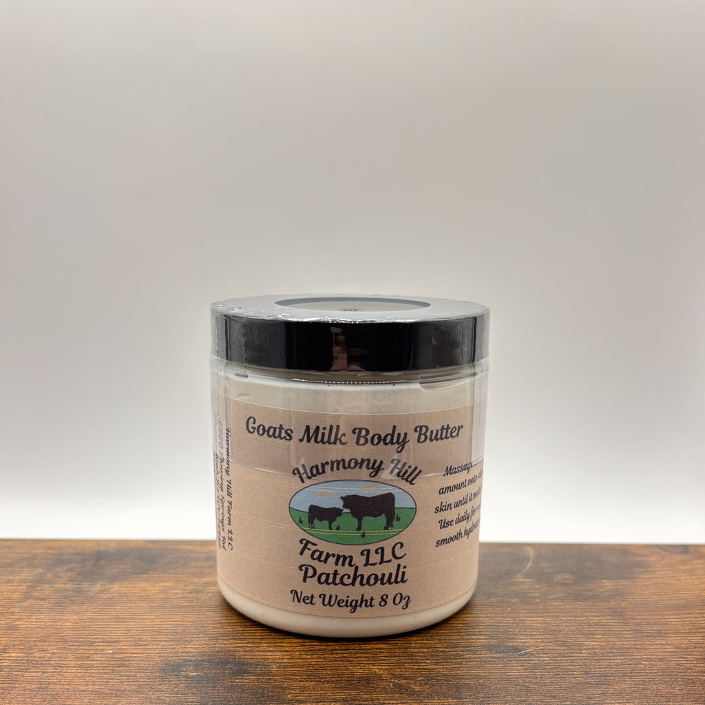Jar of patchouli goats milk body butter on a wooden surface with a white background