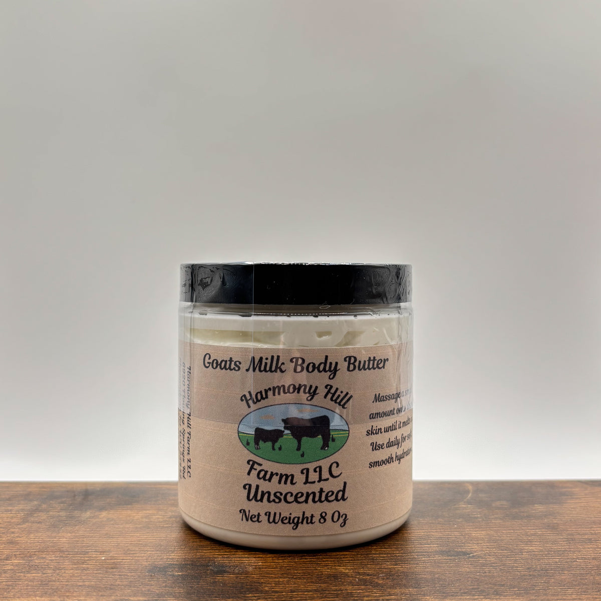 Jar of unscented goats milk body butter on a wooden surface with a white  background