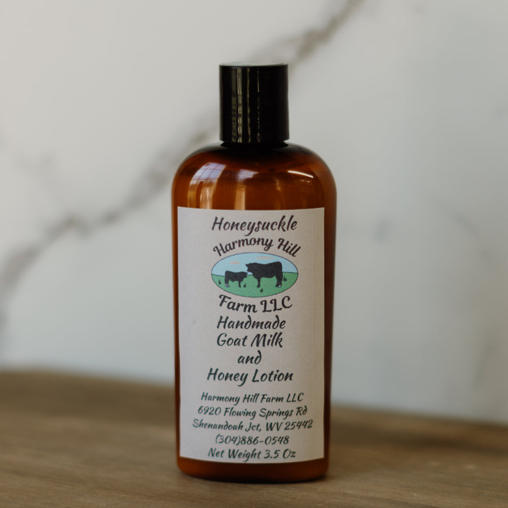 Bottle of Honeysuckle Harmony Hill Farm LLC handmade goat milk and honey lotion on a wooden surface.