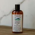 Bottle of Honeysuckle Harmony Hill Farm LLC handmade goat milk and honey lotion on a wooden surface.