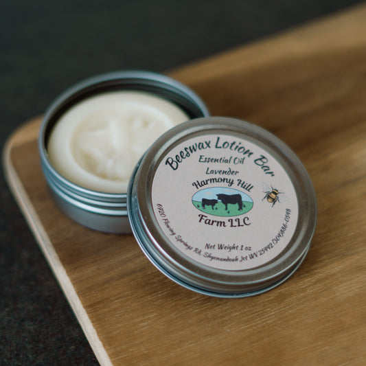 Lavender beeswax lotion bar in a tin with 'Harmony Hill Farm LLC' label on a wooden surface.