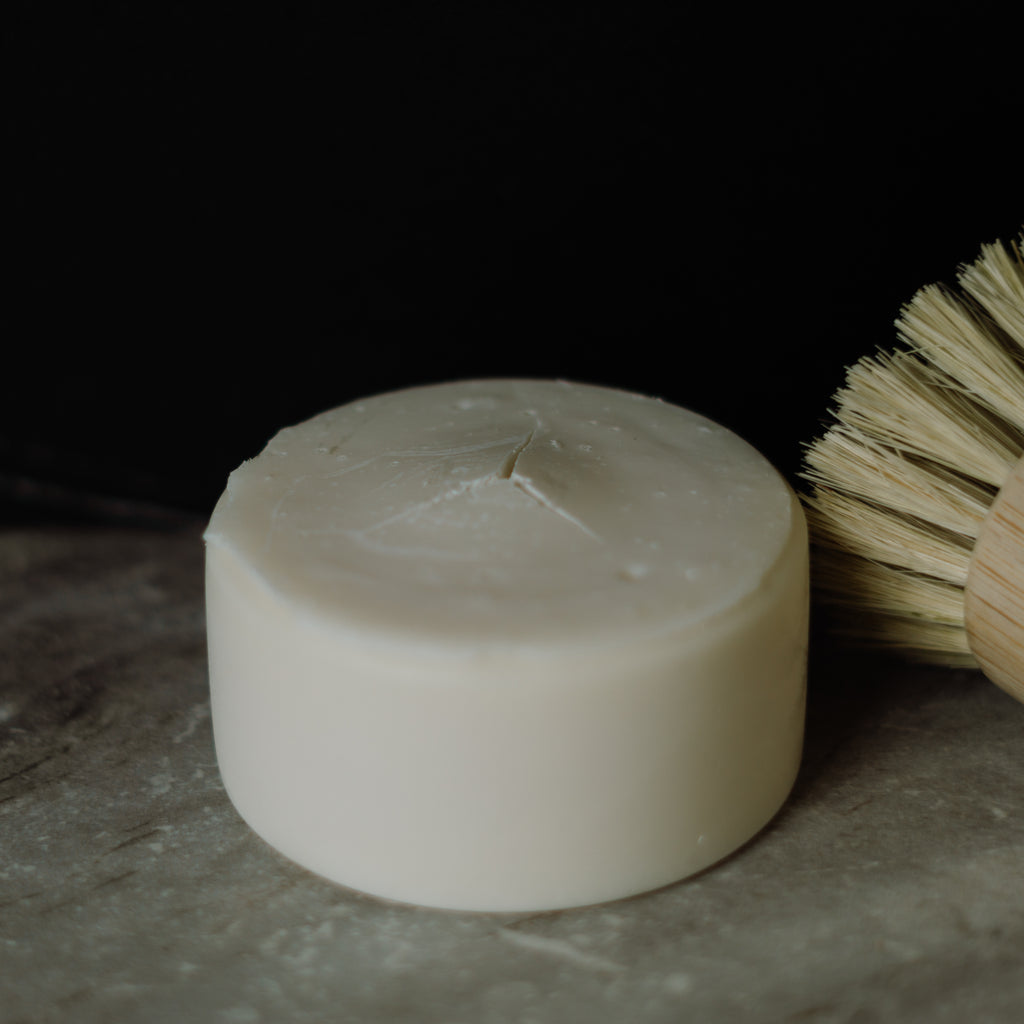 Bar of dish soap with a brush on a dark surface