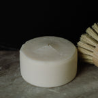 Bar of dish soap with a brush on a dark surface