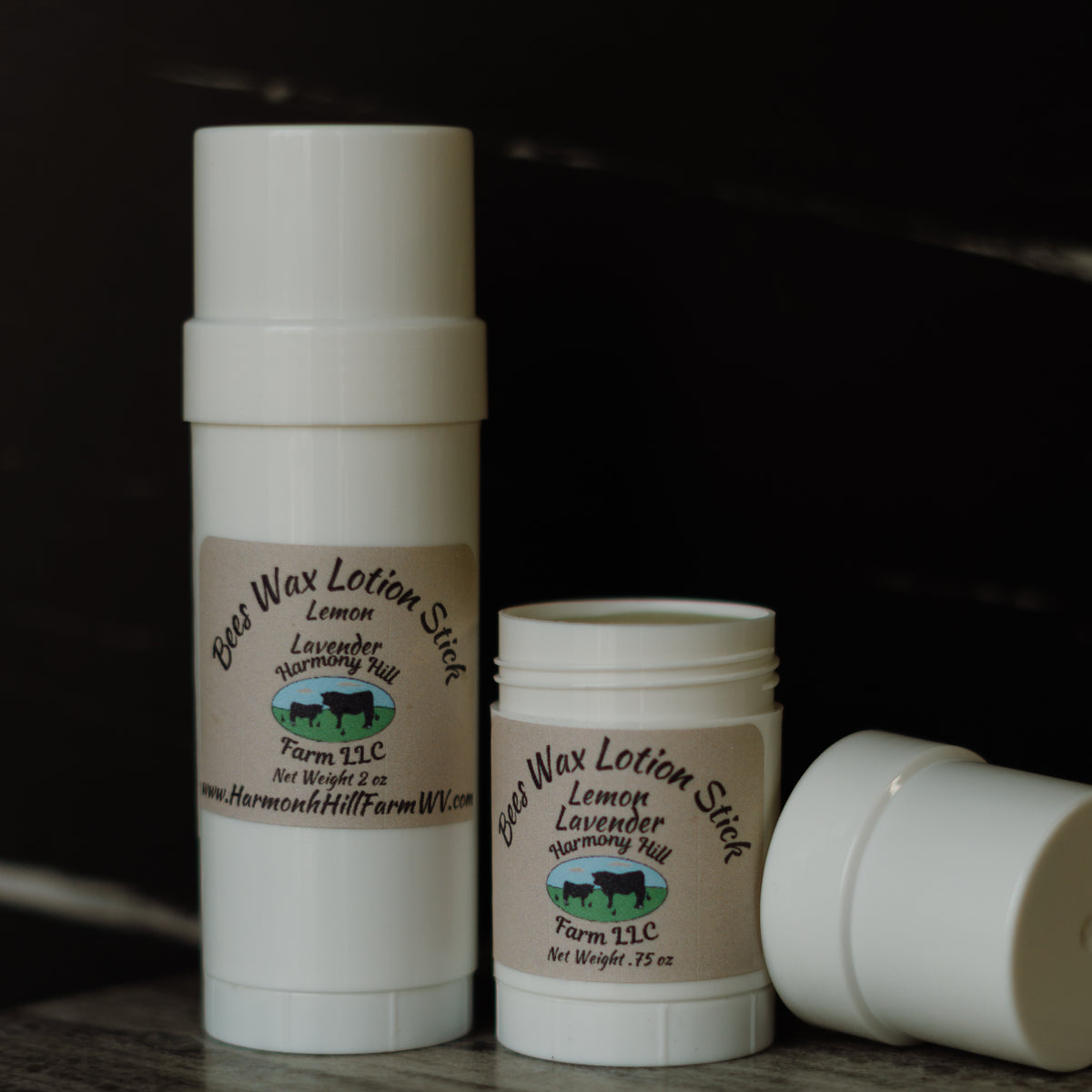 Two containers of Bee Wax Lotion Stick from Harmon Hill Farm LLC on a dark background