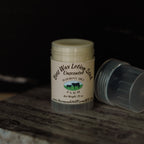 Beeswax lotion stick with visible branding on a wooden surface